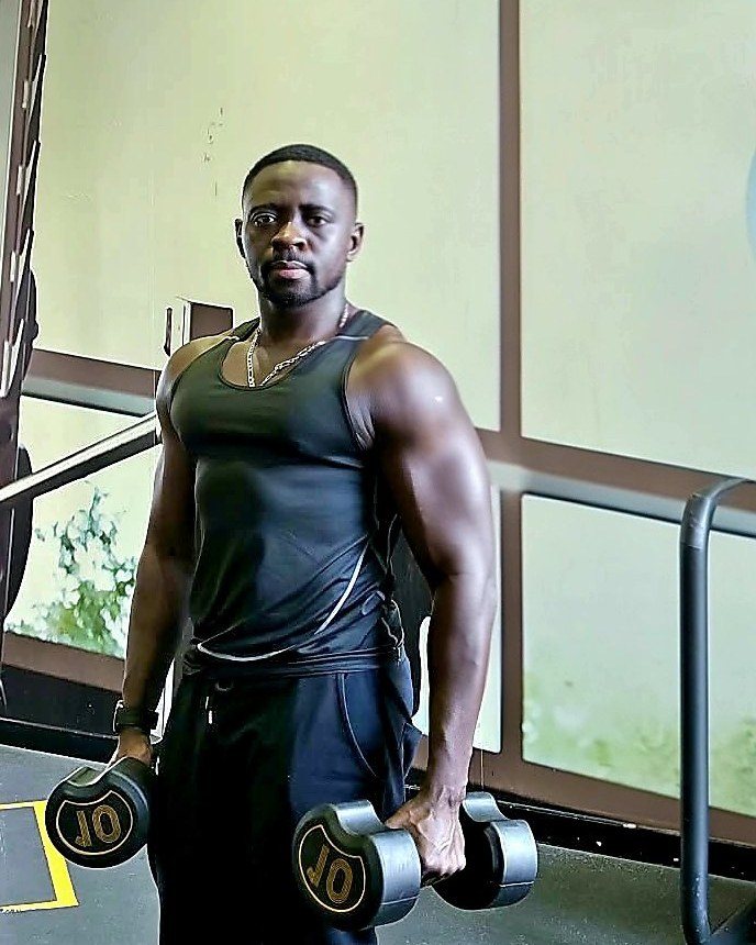 Lamin holding two dumbbells in the gym
