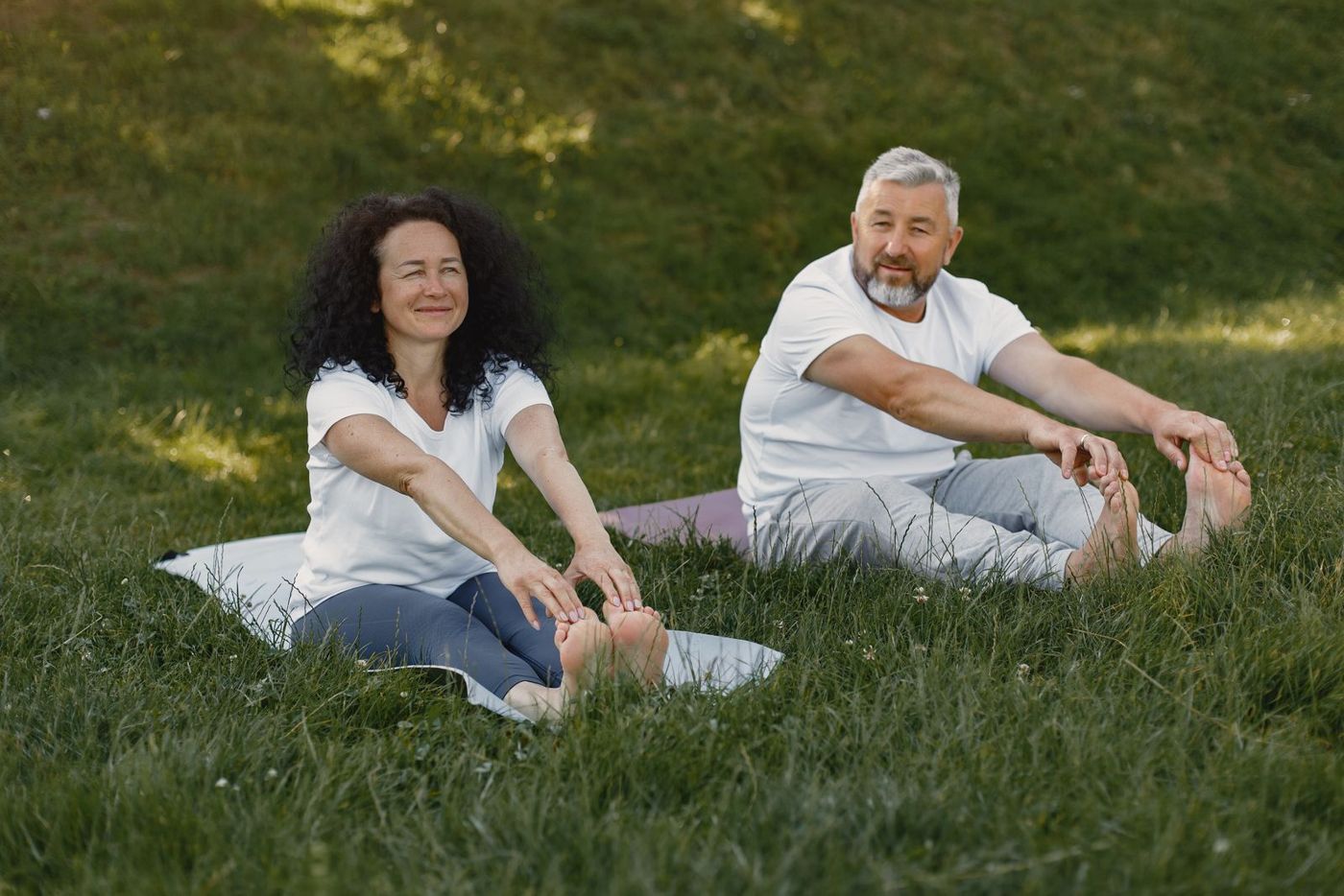 An older couple doing yoga in a park
