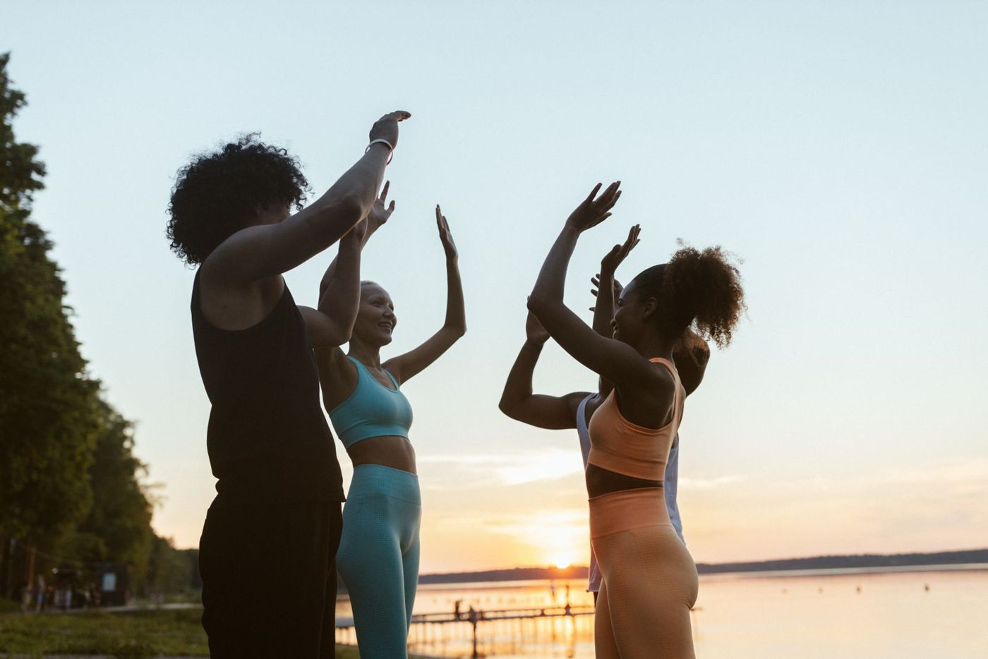 A mixed group of friends working out by a lake at sunset